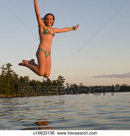 Stock Photograph - Girl jumping into a lake, Lake of the Woods, Ontario, Canada. Fotosearch