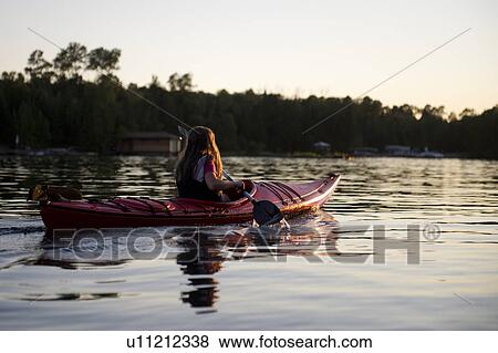 Stock Photo - Girl kayaking in a lake, Lake of the Woods, Ontario, Canada. Fotosearch