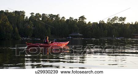 Stock Photo - Girl kayaking in a lake, Lake of the Woods, Ontario, Canada. Fotosearch