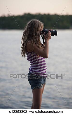 Stock Image - Girl photographing with a digital camera, Lake of the Woods, Ontario, Canada. Fotosearch