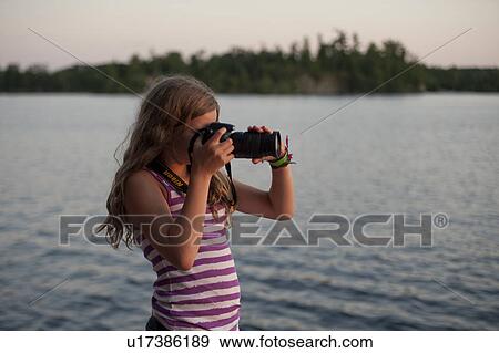 Stock Photo - Girl photographing with a digital camera, Lake of the Woods, Ontario, Canada. Fotosearch