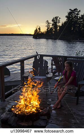 Girl sitting on a chair near a campfire, Lake of the Woods, Ontario, Canada View Large Photo Image Stock Photo - Girl sitting on a chair near a campfire, Lake of the Woods, Ontario, Canada. Fotosearch