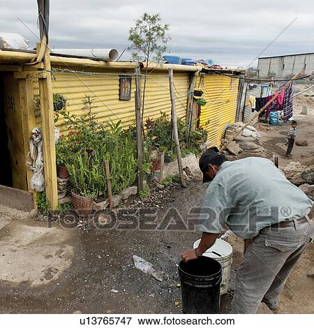 Stock Photo - Man filling water from faucet, Zona 3, Guatemala City, Guatemala. Fotosearch