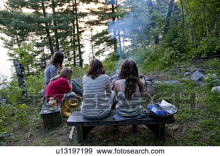 People sitting on benches near a campfire, Lake of the Woods, Ontario, Canada View Large Photo Image Stock Photo - People sitting on benches near a campfire, Lake of the Woods, Ontario, Canada. Fotosearch