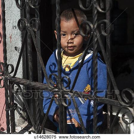Stock Photography - Portrait of a boy looking through railings, Colonia Bethania, Guatemala City, Guatemala. Fotosearch
