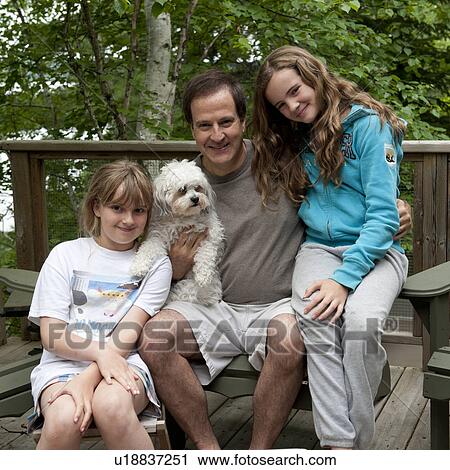 Stock Image - Portrait of a man sitting with his two daughters, Lake of the Woods, Ontario, Canada. Fotosearch