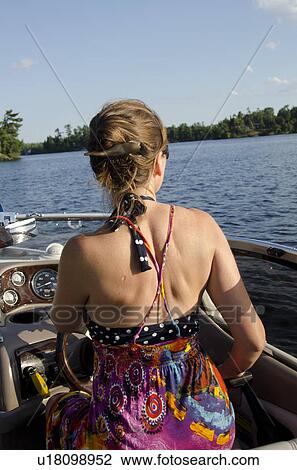 Stock Image - Rear view of a girl sitting on a boat, Lake of the Woods, Ontario, Canada. Fotosearch