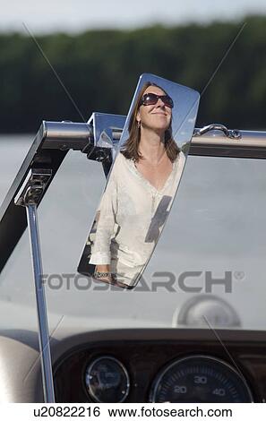 Stock Photograph - Reflection of a woman on the rear view mirror on a motor boat, Lake of the Woods, Ontario, Canada. Fotosearch