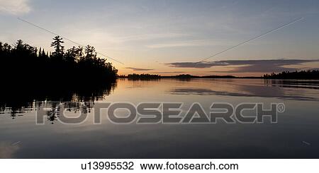 Stock Image - Reflection of trees in water, Lake of the Woods, Ontario, Canada. Fotosearch
