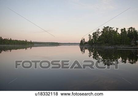 Stock Photo - Reflection of trees in water, Lake of the Woods, Ontario, Canada. Fotosearch