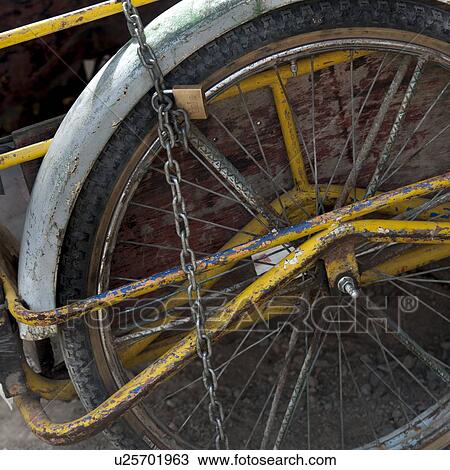 Stock Image - Rickshaw tied up with a chain and padlock, Colonia Landivar, Guatemala City, Guatemala. Fotosearch