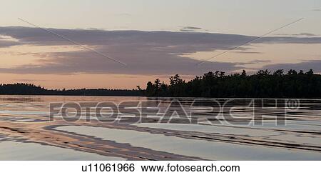 Stock Photograph - Silhouette of trees at the lakeside, Lake of the Woods, Ontario, Canada. Fotosearch