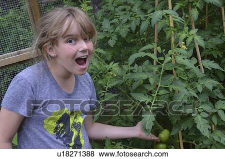 Stock Photo - Surprised girl showing tomatoes, Lake of the Woods, Ontario, Canada. Fotosearch