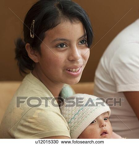 Stock Image - Teenage girl carrying a baby, San Jose Pinula, Department of Guatemala, Guatemala. Fotosearch