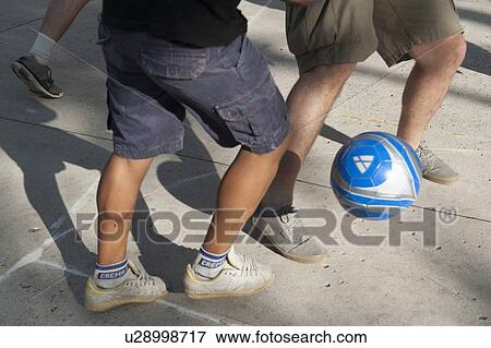 Stock Photo - Three people playing football, Colonia Bethania, Guatemala City, Guatemala. Fotosearch