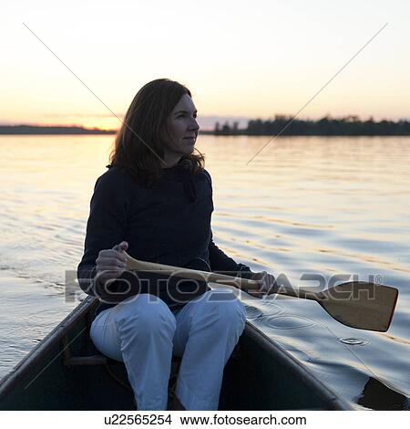 Picture - Woman rowing a boat in a lake, Lake of the Woods, Ontario, Canada. Fotosearch