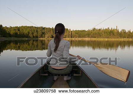 Stock Photo - Woman rowing a boat in a lake, Lake of the Woods, Ontario, Canada. Fotosearch