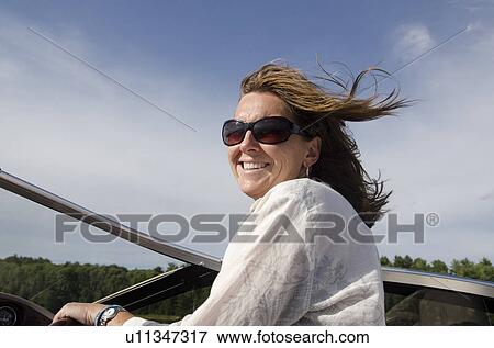 Woman standing on a boat and smiling, Lake of the Woods, Ontario, Canada View Large Photo Image Stock Photo - Woman standing on a boat and smiling, Lake of the Woods, Ontario, Canada. Fotosearch