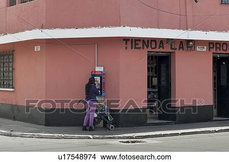 Picture - Woman standing outside a store, Colonia Landivar, Guatemala City, Guatemala. Fotosearch