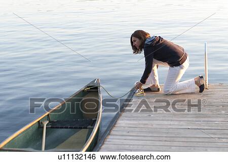 Woman tying a boat on a dock, Lake of the Woods, Ontario, Canada View Large Photo Image Stock Photograph - Woman tying a boat on a dock, Lake of the Woods, Ontario, Canada. Fotosearch