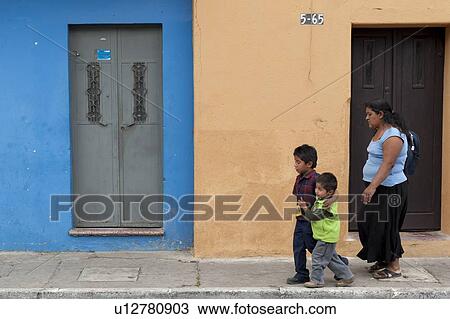 Stock Image - Woman walking with her two sons on a sidewalk, Colonia Landivar, Guatemala City, Guatemala. Fotosearch