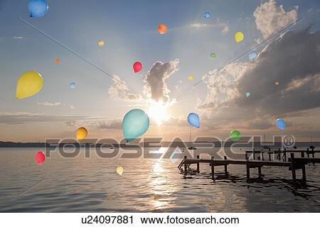 Stock Image - Balloons floating over still lake. Fotosearch