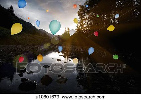 Stock Photo - Balloons floating over still rocky lake. Fotosearch