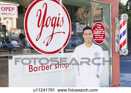 Stock Image - Barber standing outside shop. Fotosearch