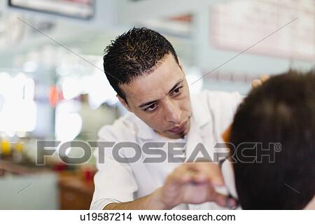 Picture - Barber working on client in shop. Fotosearch
