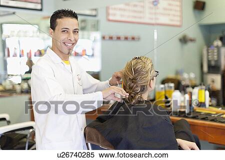 Stock Photography - Barber working on client in shop. Fotosearch