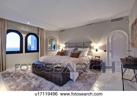 Stock Photograph - Bed and windows in modern bedroom. Fotosearch