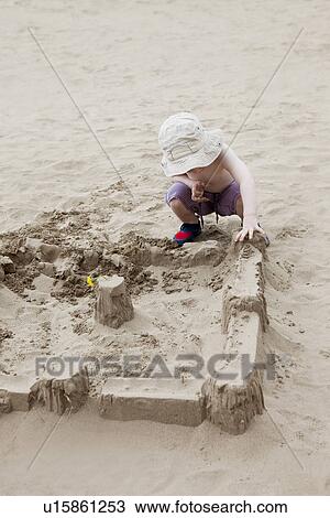 Boy building sandcastle on beach View Large Photo Image Stock Image - Boy building sandcastle on beach. Fotosearch