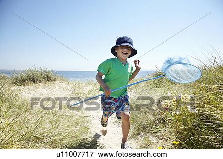 Stock Photo - Boy carrying fishing net on beach. Fotosearch