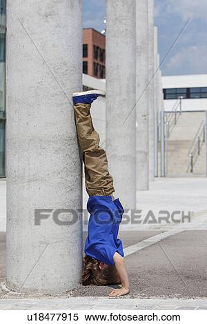Stock Photography - Boy doing headstand by column. Fotosearch