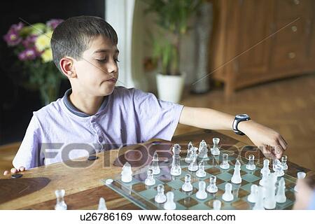 Boy playing chess in living room View Large Photo Image Stock Photo - Boy playing chess in living room. Fotosearch