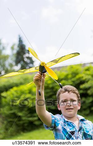 Stock Image - Boy playing with toy airplane outdoors. Fotosearch