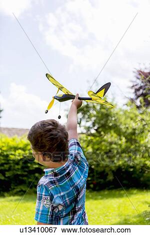 Stock Photo - Boy playing with toy airplane outdoors. Fotosearch