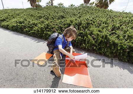 Stock Image - Boy pulling homework from folder. Fotosearch