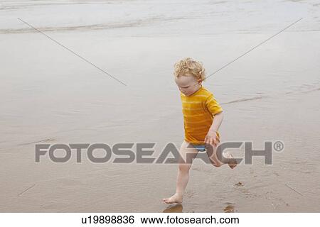 Boy running in waves on beach View Large Photo Image Stock Photograph - Boy running in waves on beach. Fotosearch