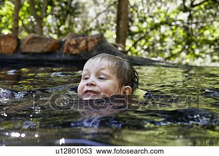 Stock Image - Boy swimming in river in forest. Fotosearch