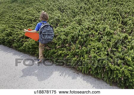 Boy walking by shrubs outdoors View Large Photo Image Stock Photography - Boy walking by shrubs outdoors. Fotosearch