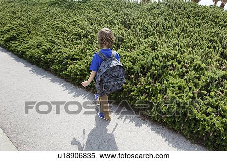 Boy walking by shrubs outdoors View Large Photo Image Stock Photography - Boy walking by shrubs outdoors. Fotosearch