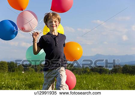 Stock Photography - Boy with colorful balloons in grass. Fotosearch