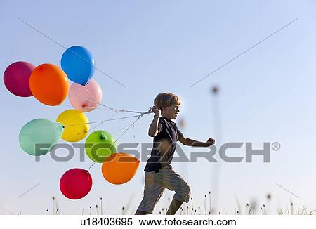 Stock Photography - Boy with colorful balloons in grass. Fotosearch