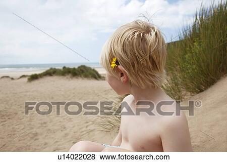 Stock Photo - Boy with flower behind his ear on beach. Fotosearch