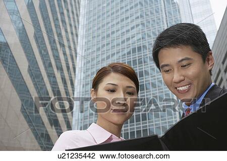 Stock Image - Business people reading on city street. Fotosearch