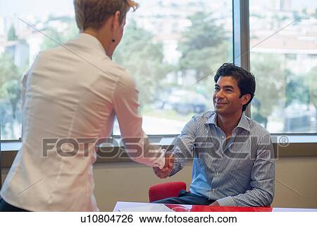 Stock Photograph - Business people shaking hands in meeting. Fotosearch