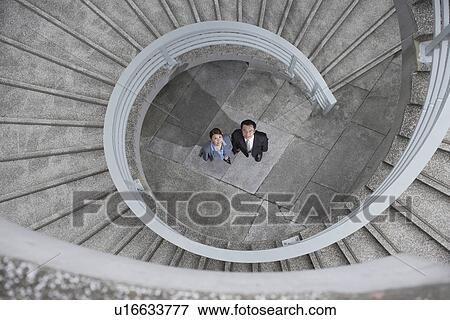 Business people under spiral staircase View Large Photo Image Stock Photo - Business people under spiral staircase. Fotosearch