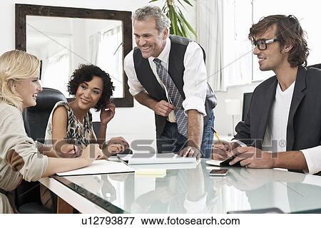 Business people working together at desk View Large Photo Image Stock Photo - Business people working together at desk. Fotosearch