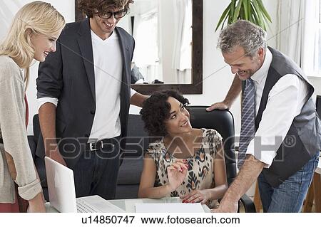 Stock Photo - Business people working together at desk. Fotosearch